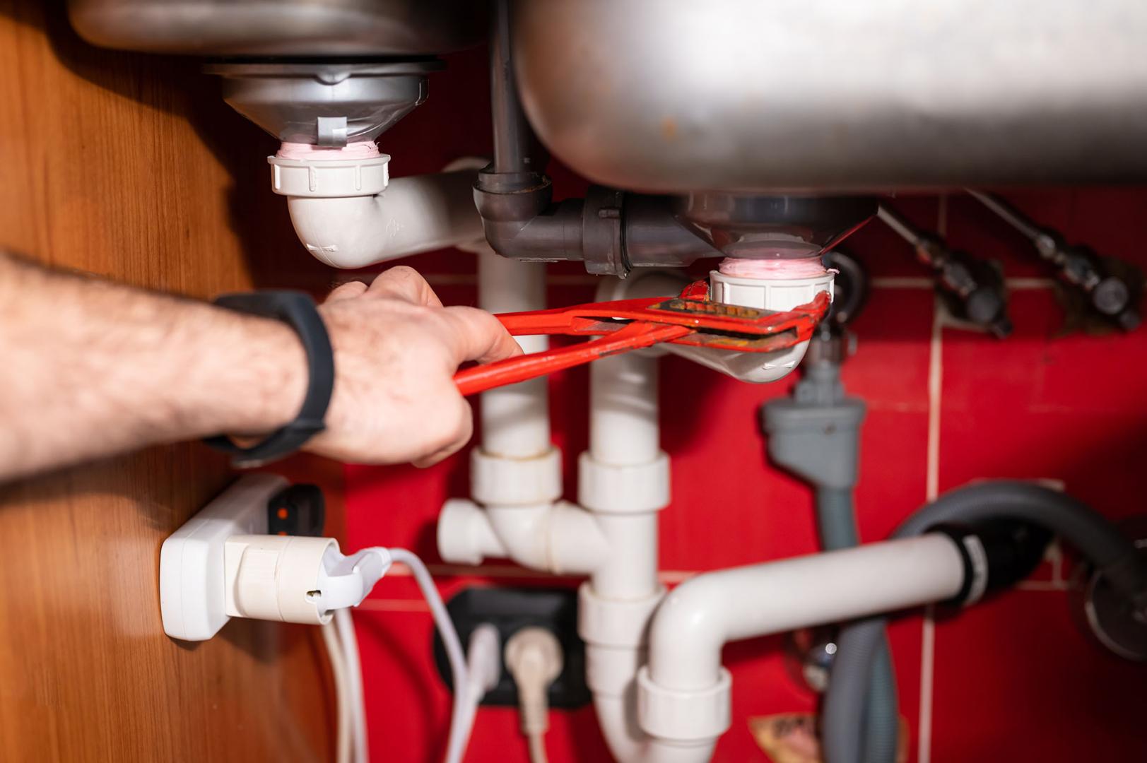 Raccords sanitaires sous un évier de cuisine — travail Arsenal Plomberie